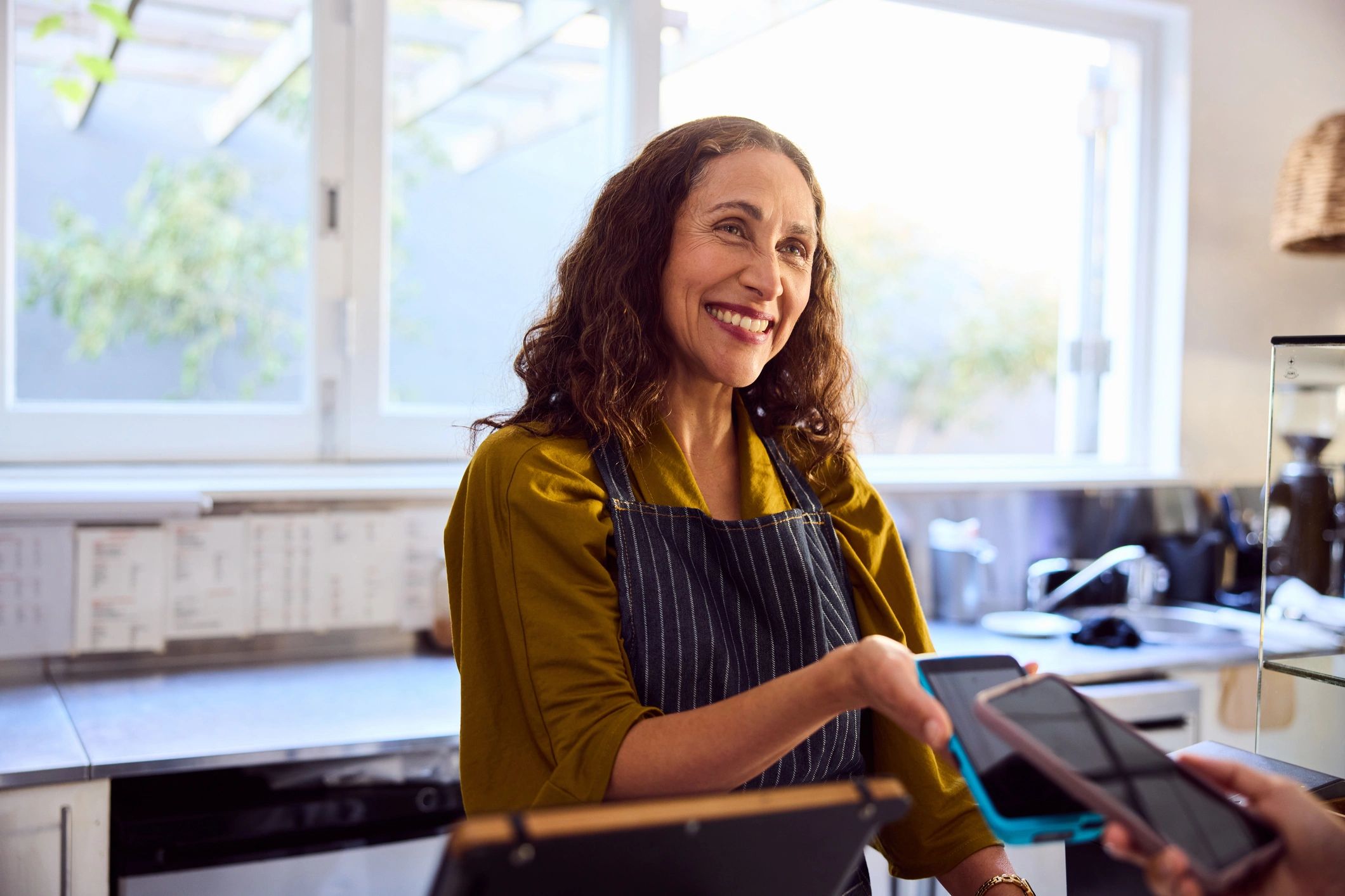 Small business owner using a smartphone at a point-of-sale counter